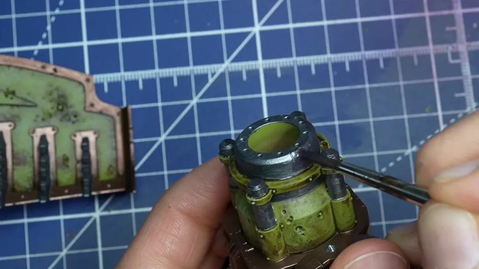 Painting the dark metal collar of an exhaust part with a brush, the dozer blade beside it, Episode 07