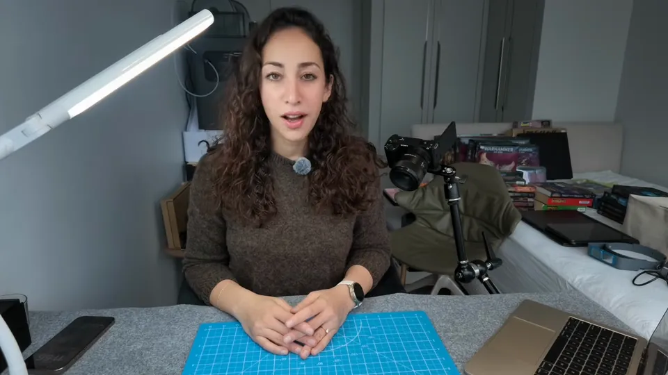 The Pigmentum at her painting desk with the cutting mat and lamp, a real frame from Episode 02